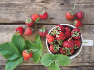 Berry strawberry theme.Strawberry in a white porcelain cup on a wooden ancient table on a gray background.Copy space.View from above.
