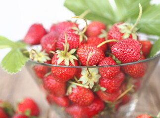 Strawberries in a glass vase on a light gray background . Copy space. Summer berry theme.