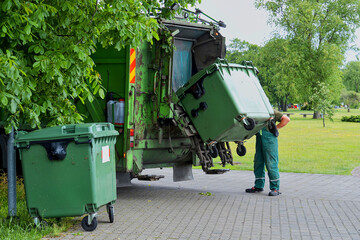 Municipal cleaning service workers remove waste with a garbage truck.