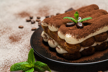 Classic tiramisu dessert on ceramic plate on concrete background
