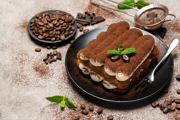 Classic tiramisu dessert on ceramic plate on concrete background