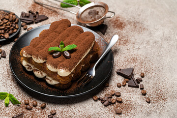 Classic tiramisu dessert on ceramic plate on concrete background