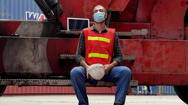 Tilt-down video shot of engineers are sitting on a forklift in a transportation industry site. He is very tired at work
