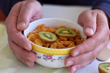 Healthy nutrition/ Man eating Delicious granola breakfast with yogurt and kiwi served on white wooden background