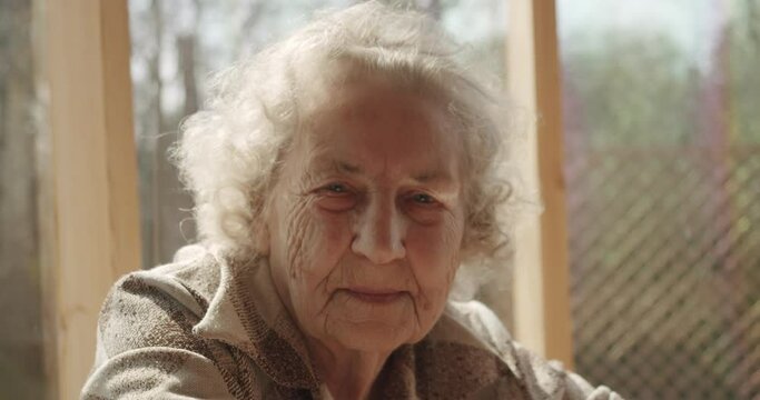 elderly woman of age stares at the camera with a wise look smiling