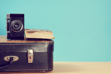 Vintage travelling background. Blogging. Retro suitcase with old book and camera, copy space. Traveler set
