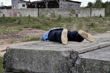 Photo of a reclining man in ruins outdoors. The concept of devastation and sadness