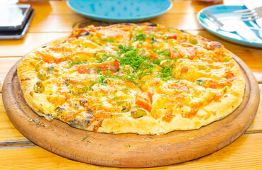Pizza with cherry tomatoes and dry basil on the wooden white plate