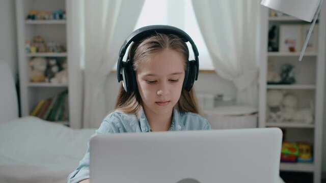 Beautiful girl student in headphone study online with internet teacher learn looking at laptop, distance education concept slow motion