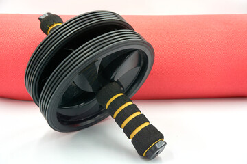 Abs roller and red yoga mat over white background