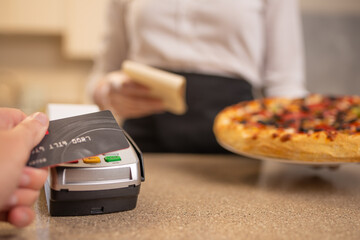 Wireless payment by card through the terminal to a waiter for Italian pizza