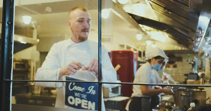 Street food cafe is opening after quarantine, waiter turns plate on window