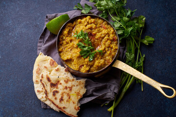 Indian red lentil curry soup dal with rice naan. Vegan indian dish on concrete background