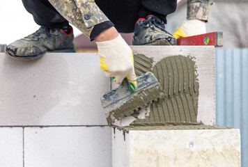 Worker puts foam concrete bricks into the wall.