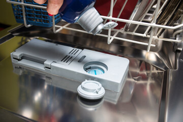 Dishwasher service. Pouring rinse liquid closeup.