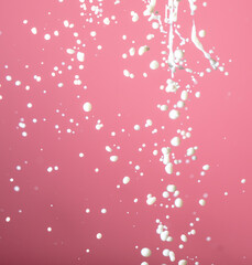 Splashes of white milk on a pink background.