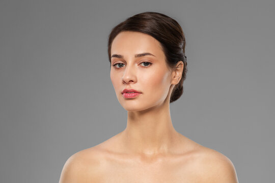 beauty, bodycare and people concept - beautiful young woman with bare shoulder over grey background