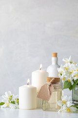 Fototapeta na wymiar Home spa resort: jasmine essential oil, candles and flowers on a white background. Spa and wellness concept.