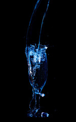 Splashes and drops of water in a glass are isolated on a black background.