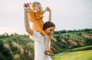 Mother with daughter walks in meadow.