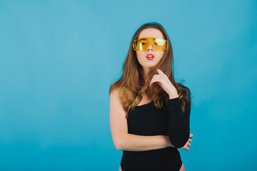 beautiful sporty girl dressed in black bodysuit with yellow glasses on blue background