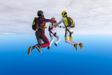 Skydiving photo. Three sports parachutist build a figure in free fall. Extreme sport concept.