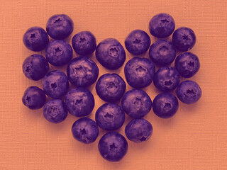 Blueberries in the shape of heart on a yellow background.