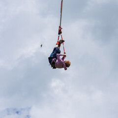 Senior lady hanging on a bungee rope high in the sky during her bungee jump. Active senior woman. Bungee jumping.