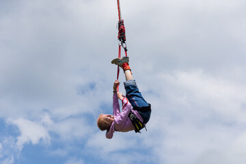 Senior lady hanging on a bungee rope high in the sky during her bungee jump. Active senior woman. Bungee jumping.