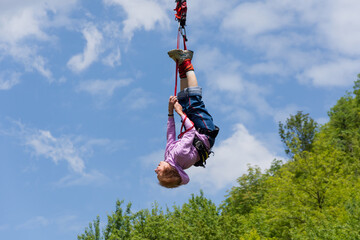 Senior lady hanging on a bungee rope, smiling happily after her bungee jump. Active senior woman. Bungee jumping.