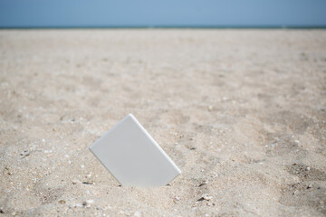 White book reader tablet at sandy beach with sea view, perfect leisure at vacation, reading novels, study and pleasure rest