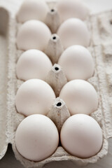Uncooked Organic White Eggs in a paper box on a white wooden background, side view. Close-up.