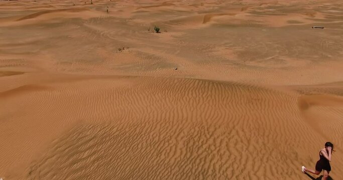 a woman walks through the desert. drone shooting