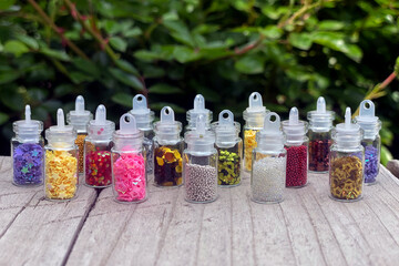 Colorful glitters for nail art and makeup in small glass jars isolated