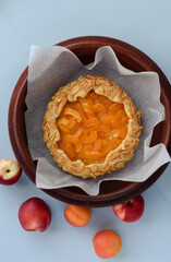 Baked galette or open apricot pie on the table. Homemade pastry