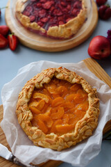 Baked galettes or open strawberry and apricot pies on the table. Homemade pastry