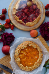 Baked galettes or open strawberry and apricot pies on the table. Homemade pastry