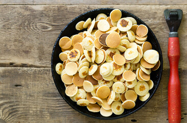 Mini pancakes in a cast iron pan on wooden table