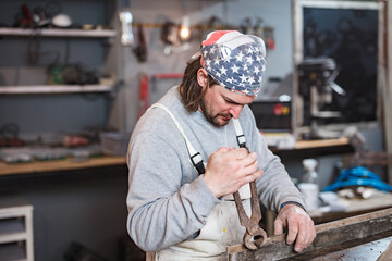 Male carpenter working on old wood in a retro vintage workshop.