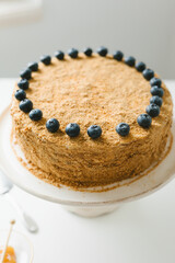 Homemade honey cake with milk cream and blueberries.