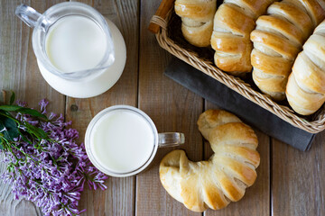 Rosy bagels with jam, a jug of milk and a glass of milk on a wooden table. The view from the top
