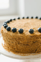 Homemade honey cake with milk cream and blueberries.