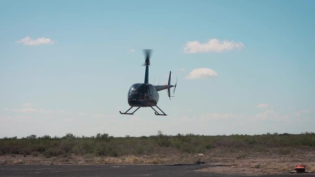 Helicopter approaching a landing on asphalt runway on a sunny day slow motion