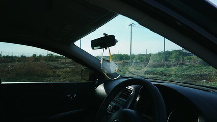 Fototapeta premium N95 respirator face mask is hanging under rear view mirror in a car for going outside during covid19 pandemic, viruses and pm 2.5 protect in car