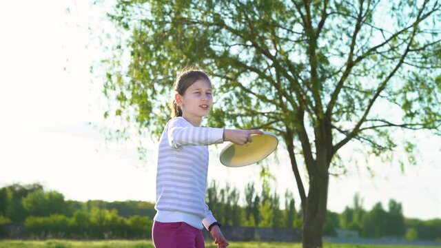 Little girl having fun with plastic disc in sunny park