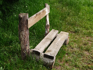 Wooden bench in green grass in the meadow