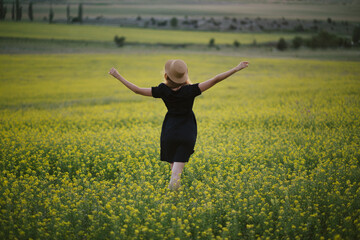 Young beautiful woman relaxing in summer field of yellow flowers.