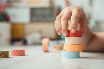 Hand of a child doing a tower with washi tape rolls