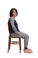side view of a woman in pajamas sitting o a chair on white backgroun,looking at camera