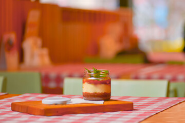 A jar of sweet and delicious dessert with caramel and peanut butter. Salty dessert. Peanuts. Served on a wooden board.